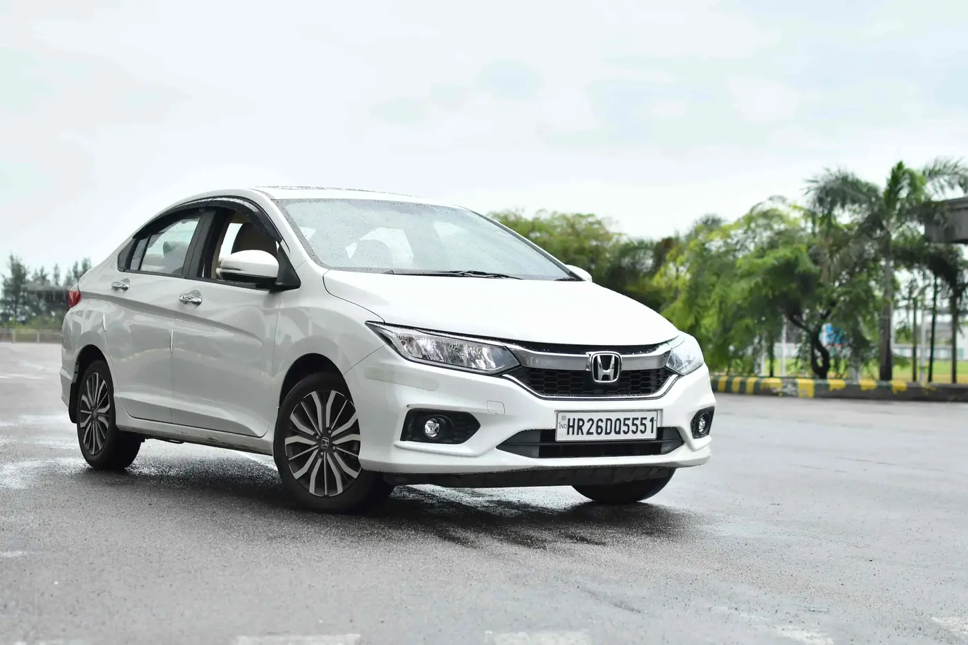 White Honda City sedan waiting on the apron road for a Mangalore airport pickup